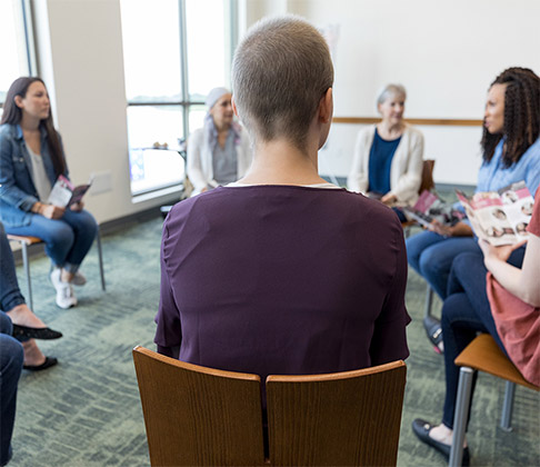 Warm image of a support group of women who have their cancer in remission, seated in a circle sharing their support stories.